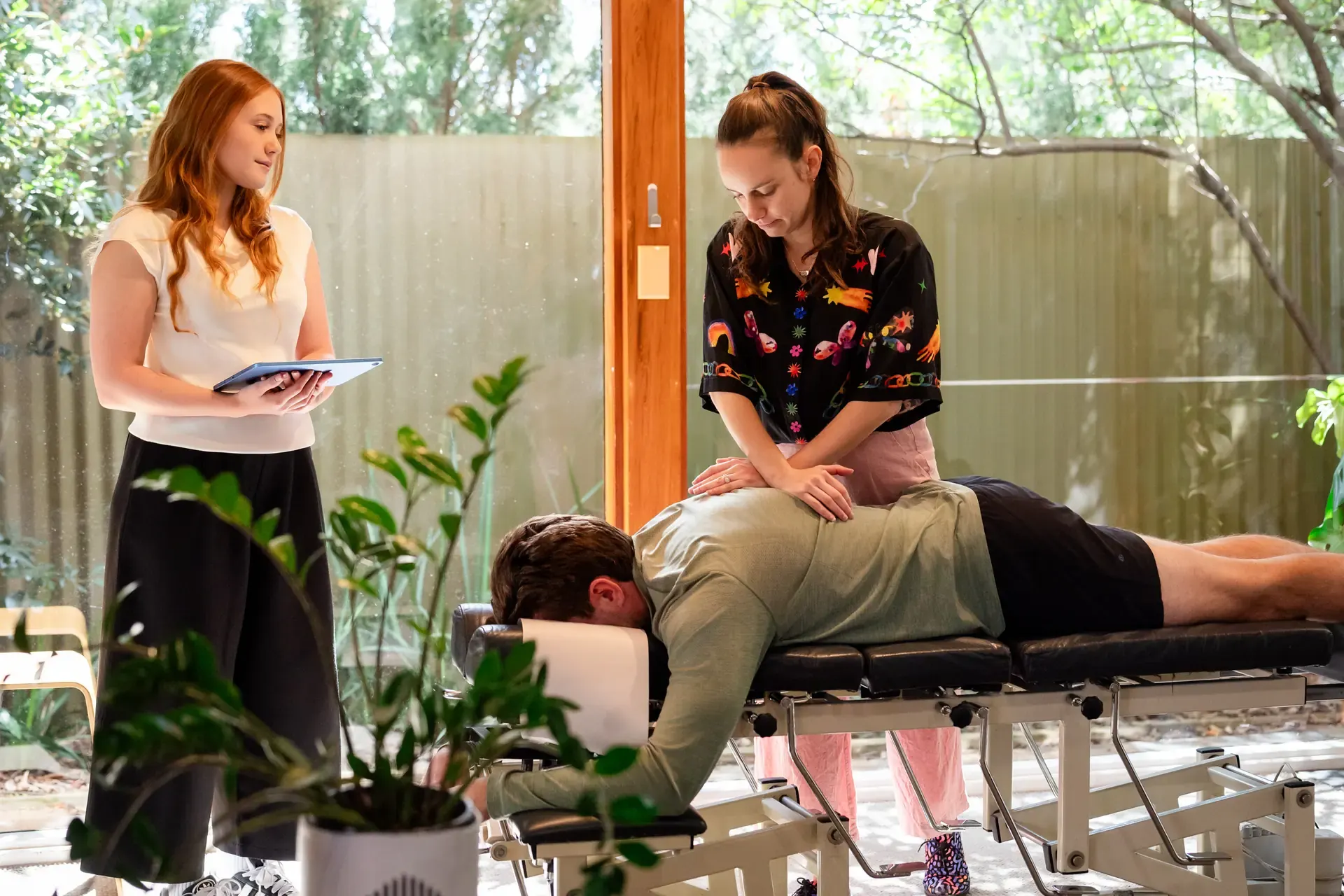 Dr Adelle Semmler adjusting a person while Abella records notes at The Chiro Crew in Kingswood
